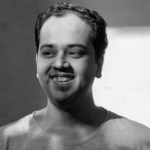Black and white photo of a man smiling, looking away from camera (Dhruv Jani)