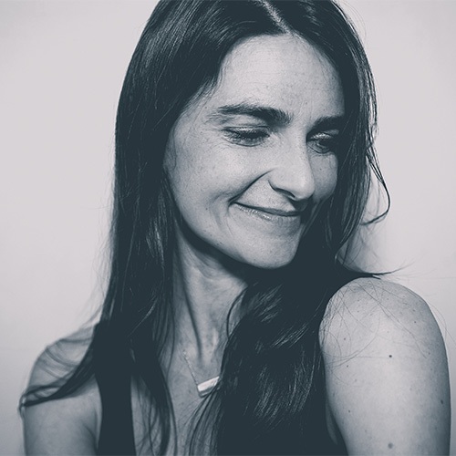 Black and white photo of a woman smiling, looking away from the camera (Georgia Simms)