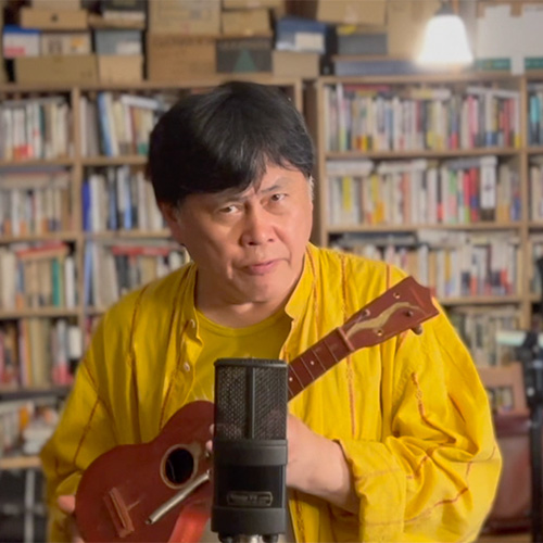 Photo of man holding ukulele, looking at the camera (Koichi Makigami)