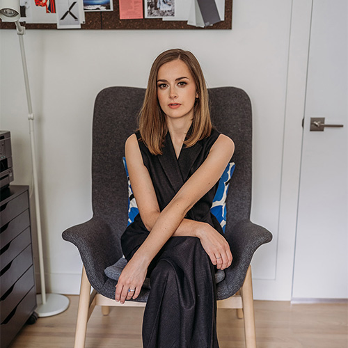 Photo of woman sitting cross-legged on a chair, looking at the camera (Lucy Bilson)